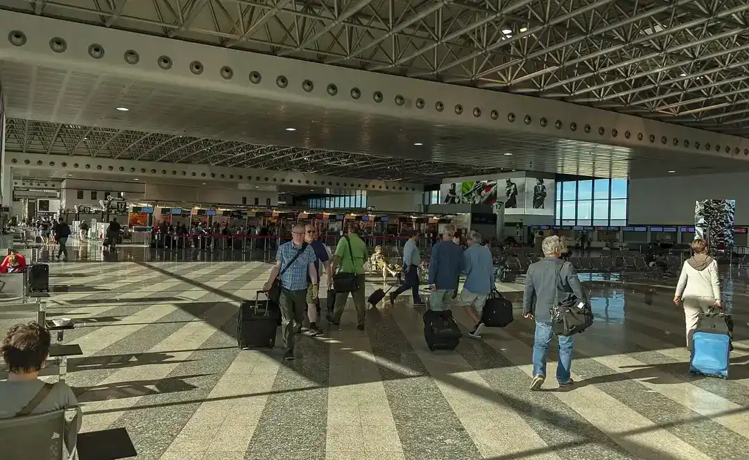 Airport check-in hall with travellers and suitcases